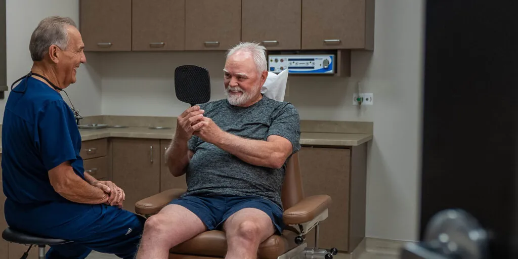 Team member Smiling into mirror after dental implant surgery